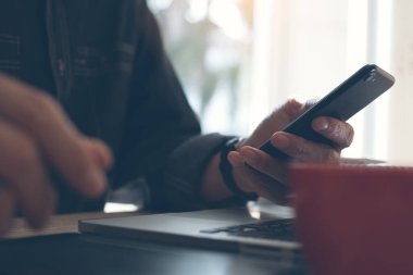 Sıradan bir iş adamı, cep telefonu kullanan serbest çalışan, dizüstü bilgisayar kullanan, dijital tablet kullanan kahve dükkanında bir fincan kahve içen,