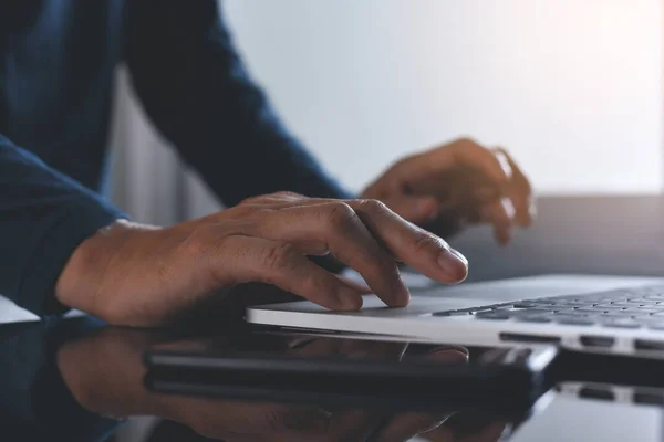 Evdeki cep telefonuyla dizüstü bilgisayarda çalışan sıradan bir adamın görüntüsü. Evden bağımsız çalışma, taşınabilir ofis kavramı