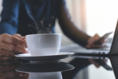 Çoklu görev adamı, bilgisayar başında çalışırken cep telefonu kullanan serbest çalışan ve ofis masasında yansımasıyla evde kahve içen biri.