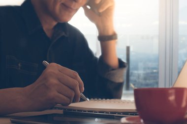 Sıradan bir iş adamı, cep telefonuyla arayan, not defterine yazan, kahve dükkanında dizüstü bilgisayarda çalışan, serbest çalışan, online çalışma konsepti olan,