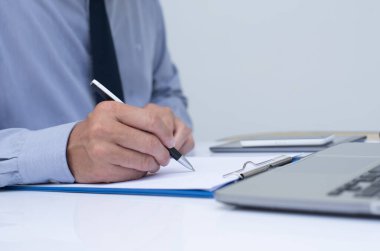 Not etmek üstünde yazma ve office odada dizüstü bilgisayar üzerinde çalışan iş adamı yakın çekim.