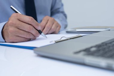 Not etmek üstünde yazma ve office odada dizüstü bilgisayar üzerinde çalışan iş adamı yakın çekim.