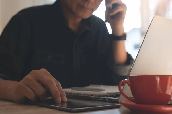 Gündelik iş adamı, serbest çalışan telefon görüşmesi, ev ofisinde bilgisayarla dijital tablet üzerinde çalışmak masada bir fincan kahve, serbest çalışan online çalışma konsepti, kapat.