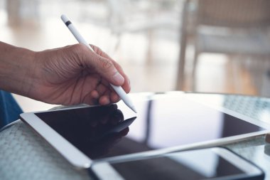 Dijital tablet bilgisayarda stilus kalem kullanarak insan elini kapat. Kafede tablet bilgisayarı üzerinde çalışan serbest grafik tasarımcısı, kapat