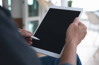 Kafede ya da restoranda boş siyah ekran dijital tablet bilgisayarına dokunan sıradan bir adamın ellerinin görüntüsünü taklit et, omuz manzaralı, kapat