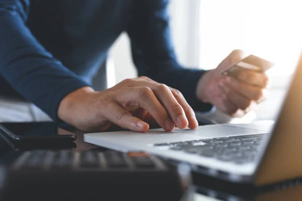 Çevrimiçi ödeme, dijital bankacılık. Hesap makinesi ve cep telefonuyla online alışveriş yapmak için kredi kartı kullanan bir adam. Kapat. Siber Pazartesi, ticaret konsepti