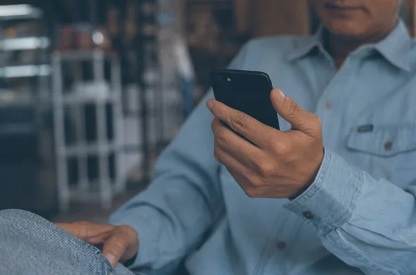 Casual business man relaxed checking internet application on phone, man using smartphone and browsing internet in cafe or coffee shop during waiting for someone, vintage tone, internet of things