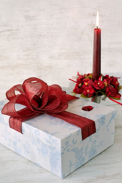 Geschenkdoos met rode kaars op houten achtergrond — Stockfoto