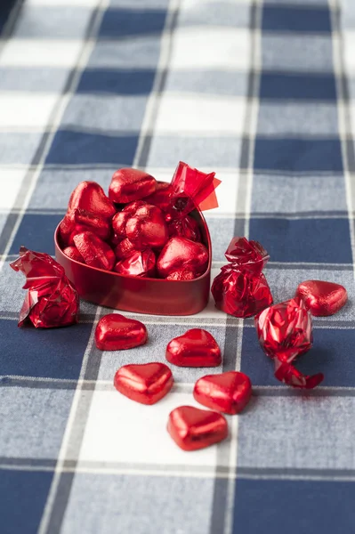Καρδιά σχήμα κόκκινο μεταλλικό κουτί με γλυκά σοκολάτες. κινηματογράφηση σε πρώτο πλάνο. — Φωτογραφία Αρχείου