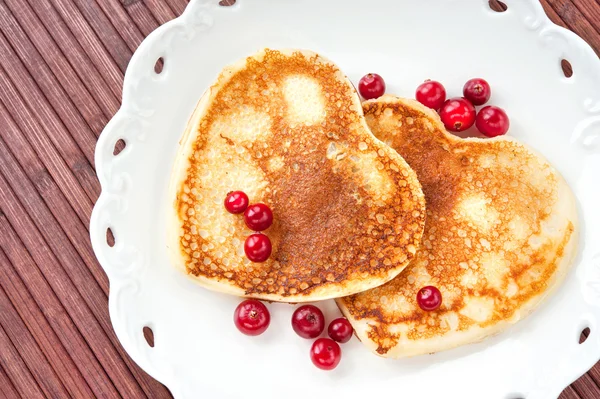 Heart shaped pancakes with cranberries on porcelain plate. Close — Stock Photo, Image