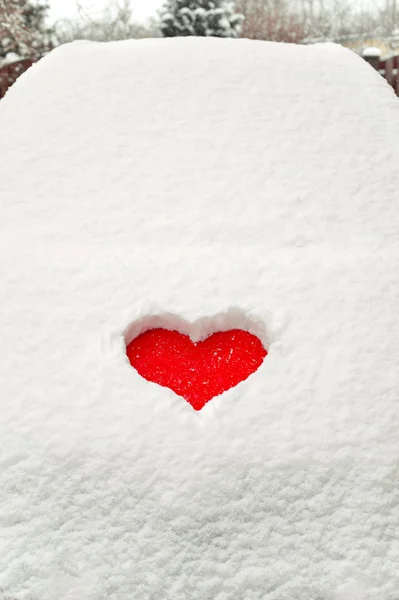 Amour rouge forme de coeur dans la neige sur la voiture rouge. Gros plan . — Photo