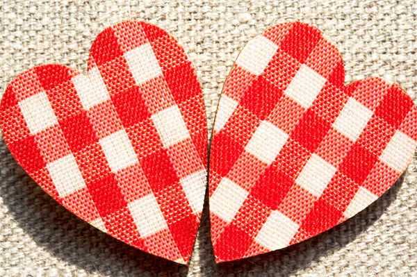 Dos corazones rojos de amor a cuadros sobre fondo de arpillera . — Foto de Stock