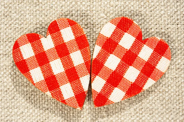 Twee rode geruite liefde harten op jute achtergrond. — Stockfoto