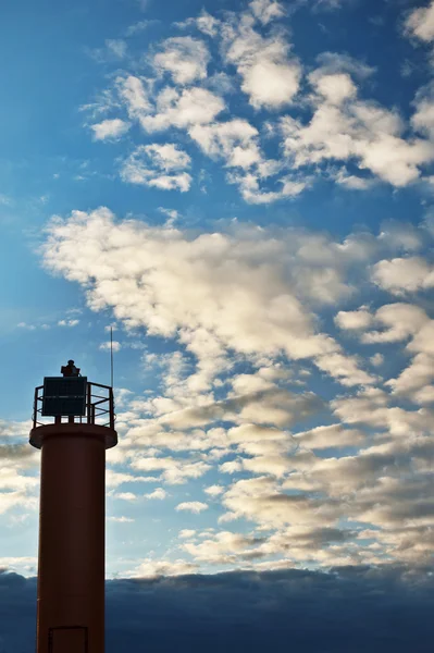 Fond bleu ciel nuageux avec phare de balise dessus . — Photo