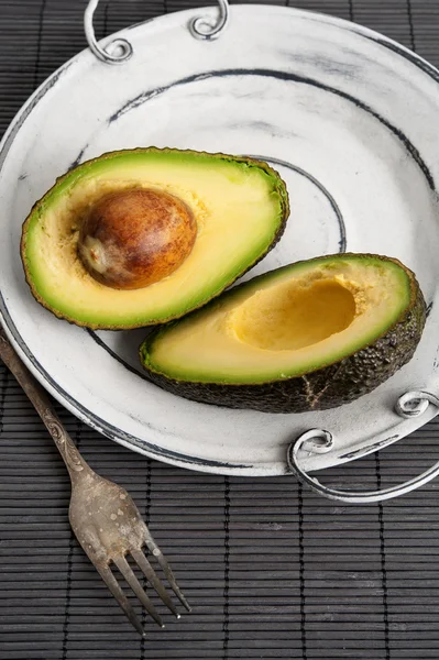 Halbierte Avocado auf Vintageteller. Nahaufnahme. — Stockfoto