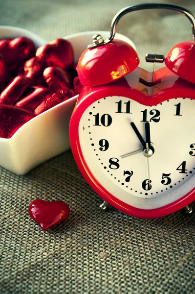 Horloge rouge en forme de coeur avec chocolats sucrés — Photo