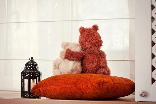 Two embracing loving teddy bears sitting on window-sill. — Stock Photo, Image