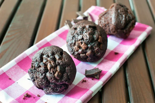 Delicious homemade chocolate muffins on checkered tablecloth. — Stock Photo, Image