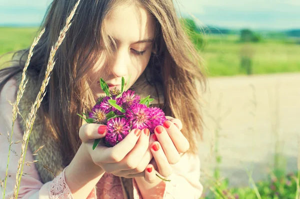 自然の美しさ。紫草原クローバーの花の臭いがする美しい少女 — ストック写真