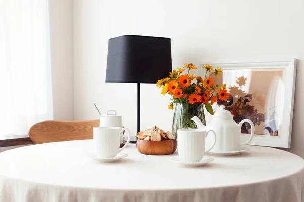 白いテーブルクロスと花の花束と朝の新鮮なお茶のための丸いテーブル お茶の時間を設定します ダイニングルームでの屋内水平静物 — ストック写真