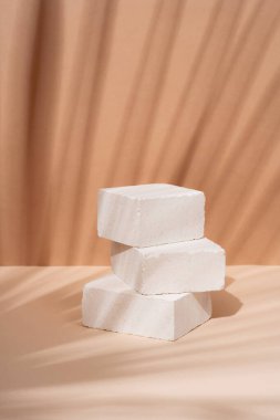 Kozmetik ürünleri için arka planda tropikal bir yaprağın gölgesi olan doğal taştan yapılmış podyum. Doğal maddelerden güzel bir arkaplan