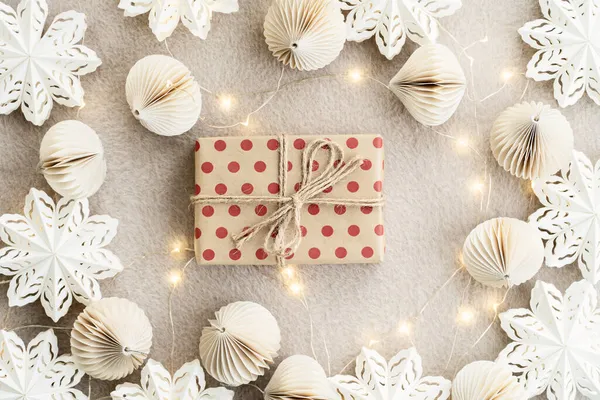 Caixas de presente de papel bege em um tapete bege luzes guirlanda de Natal e decorações de Natal feitas de papel. Conceito de celebração Ano Novo. — Fotografia de Stock