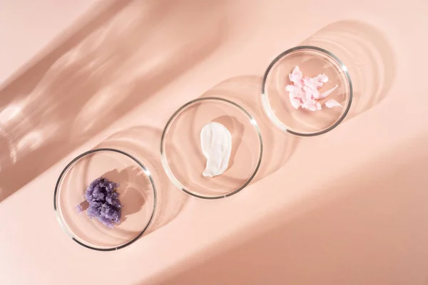 Cosmetic products, scrub, face serum and gel in many petri dishes on a pastel beige background. Cosmetics laboratory research concept. — Stock Photo, Image
