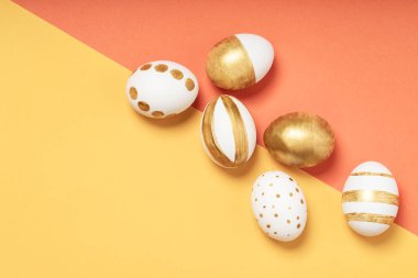 Sarı ve turuncu pastel arka planda el yapımı paskalya yumurtaları. Birçok Paskalya yumurtası düz arkaplanda yatar.
