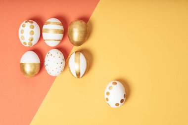 Sarı ve turuncu pastel arka planda el yapımı paskalya yumurtaları. Birçok Paskalya yumurtası düz arkaplanda yatar.
