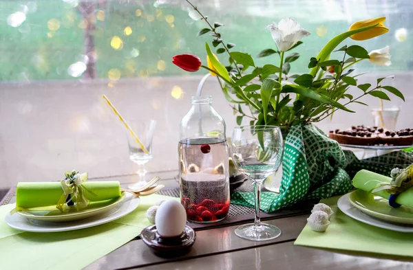 Bahar kahvaltısı için yeşil pastel renkli masa, Paskalya yemeği ve lale çiçekleri.