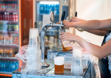 Kadın barmen bar tezgahında bira fıçısından bira dolduruyor.