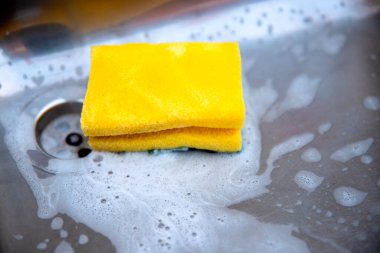 Mutfak lavabosundaki sarı sünger yakın plan. Evdeki kirleri ve mikropları temizlemek.