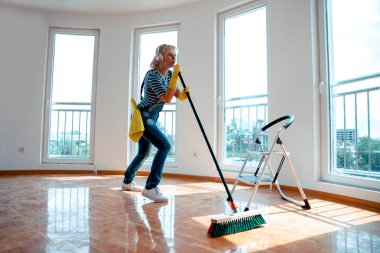 Mutlu Kadın yeni evi temizlerken kulaklıkla dans edip şarkı söylüyor. Uzayı kopyala Partiden sonra evi temizlemek