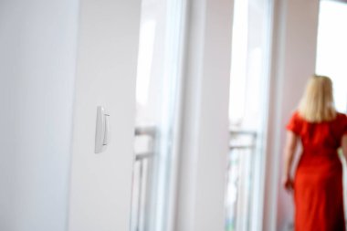 Duvar lambası düğmesi ve oturma odasındaki kadın. Boşluğu kopyala