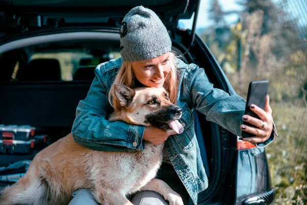 Arabasının bagajında köpeğiyle oturan bir kadın gezgin. Yol arasında dinleniyorum.
