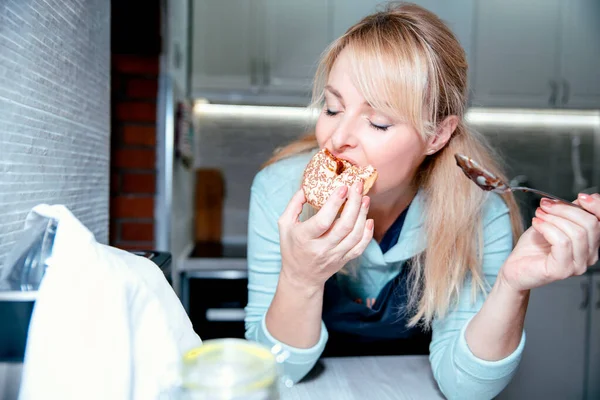 Mulher Loira Comendo Donuts Com Geléia Leite Sentada Cozinha Desfrutando — Fotografia de Stock