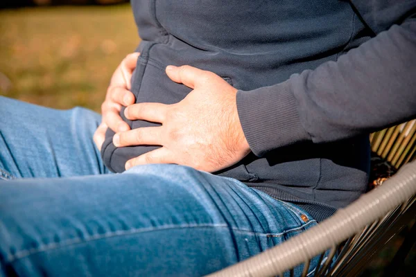 Adamın mide ağrısı var, kabızlıktan, karın üstü el ele tutuşmaktan. Yakın çekim.