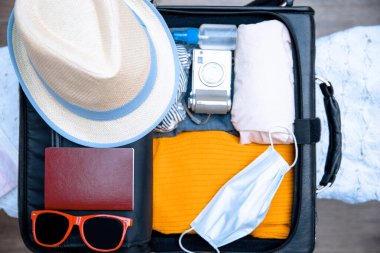 Packing suitcase luggage with face mask and sanitizer with clothes for new normal travelling during Coronavirus pandemic