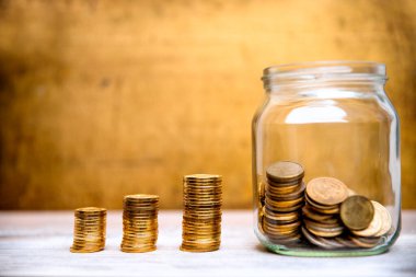 Ahşap arka planda cam kavanozda sikkeler