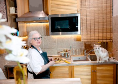 Son sınıf öğrencisi kadın mutfakta yemek pişiriyor.