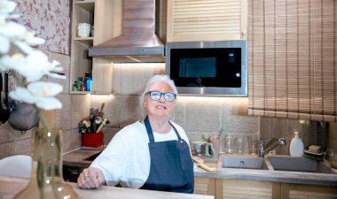 Son sınıf öğrencisi kadın mutfakta yemek pişiriyor.