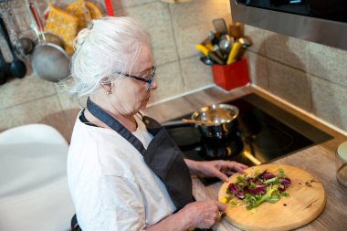 Son sınıf öğrencisi kadın mutfakta yemek pişiriyor.