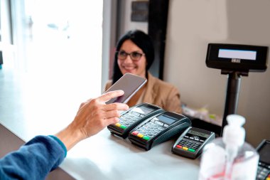 Kadın kredi kartı ve NFC teknolojisiyle ödeme yapıyor.