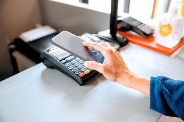 Kadın ödemeyi akıllı telefonla yapıyor.