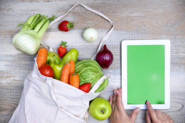 Tablet bilgisayar ekranı ve taze sebzeler ve ahşap masada meyveler, düz yat, kapat. İnternetten alışveriş kavramı