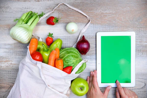 Tablet bilgisayar ekranı ve taze sebzeler ve ahşap masada meyveler, düz yat, kapat. İnternetten alışveriş kavramı