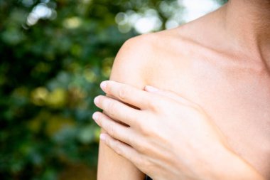 Kadın eli açık havada acılı ve çıplak omzunda. Kadın omzuna dokunuyor, pürüzsüz tenine. Cilt değişimi kavramı denetleniyor