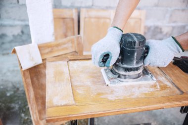 Kadın marangoz ahşap dolapta zımpara makinesi ile çalışıyor. Kadın restorasyonu ve eski ahşap mobilyaların tamiri. DIY Evde El Sanatı