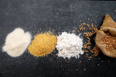 Fırın siyah yüzeyinde farklı buğday gevreği unu. Değirmende dört buğday, öğütülmüş buğday filizleri, irmik unu, halis. Düz yatıyordu yukarıdan.