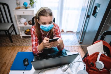 Genç Kız online eğitim başvurusu için dizüstü bilgisayar kullanıyor. Coronavirus salgını sırasında evdeki video sınıfındaki çocuk